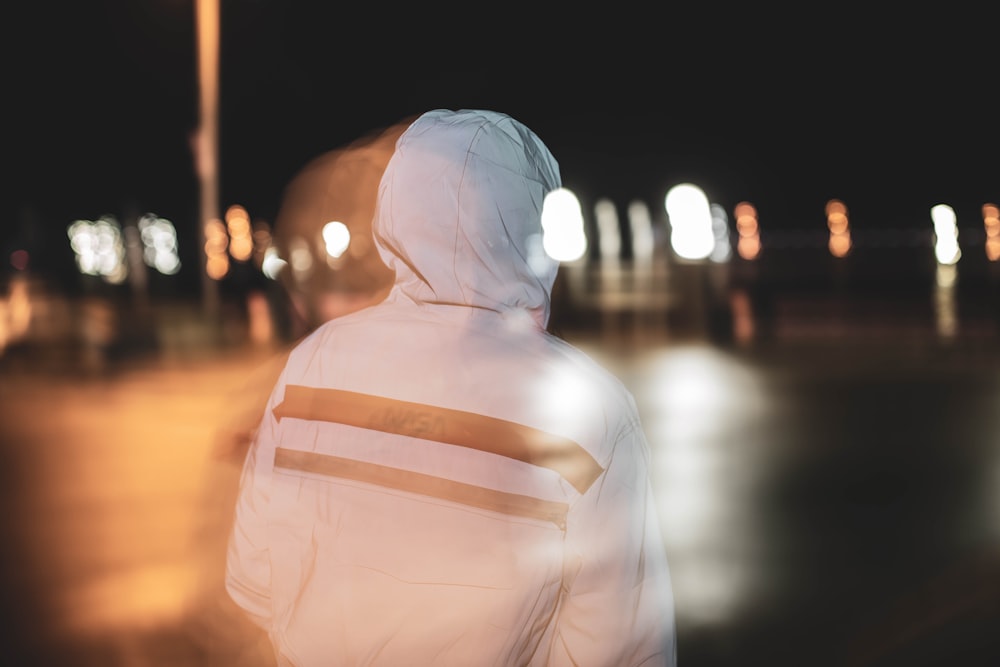 person in white hoodie standing during night time