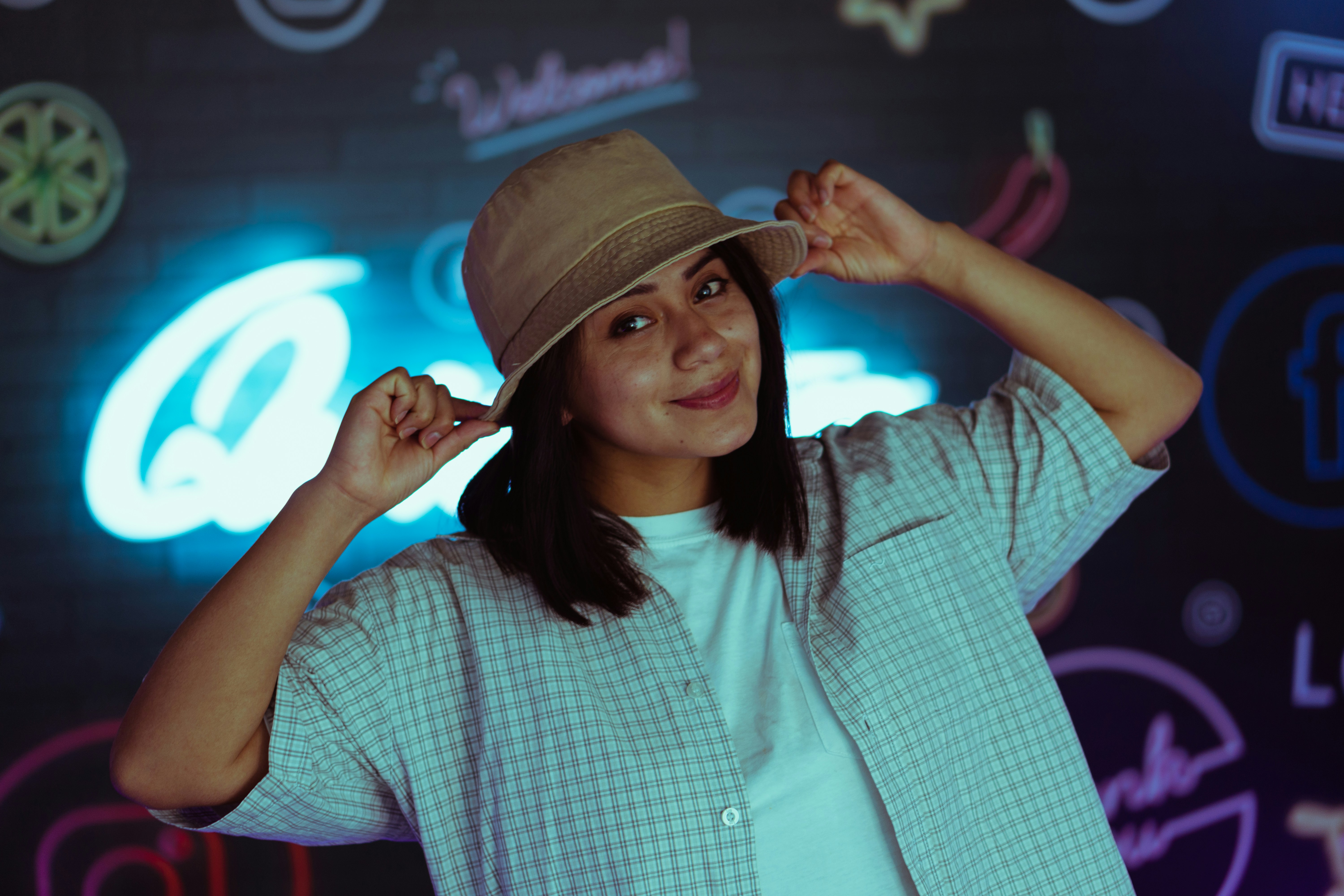 Wanita dengan kemeja kancing kotak-kotak biru dan putih mengenakan topi Fedora coklat
