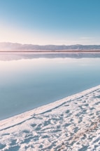 body of water near snow covered mountain during daytime