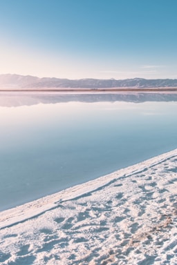 body of water near snow covered mountain during daytime