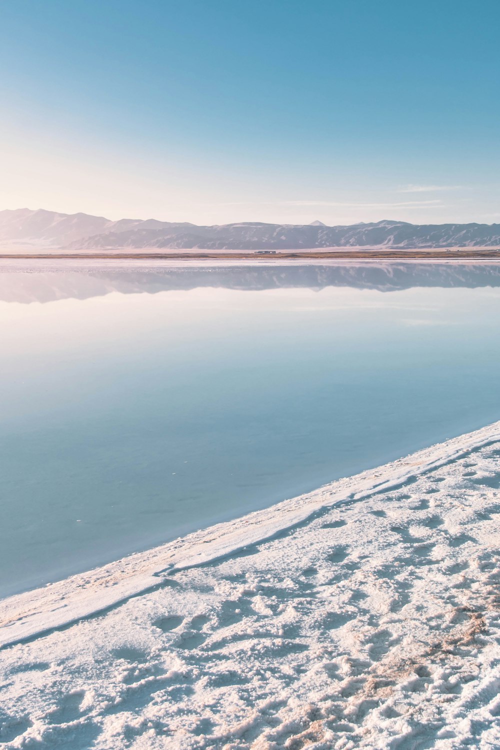 body of water near snow covered mountain during daytime