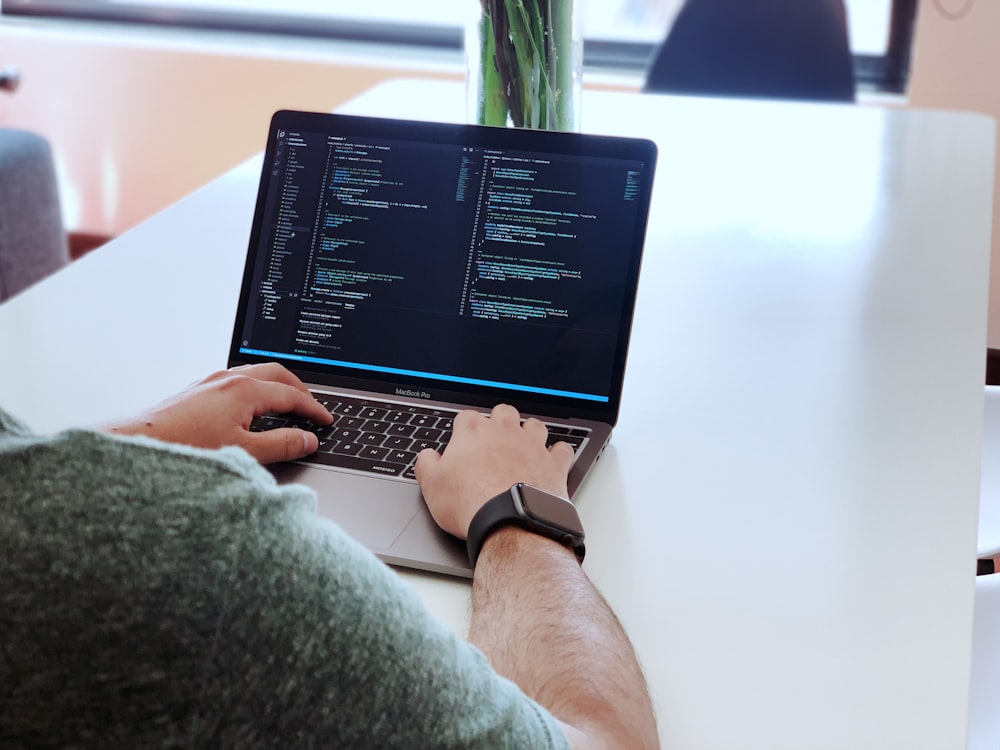 person using macbook pro on table