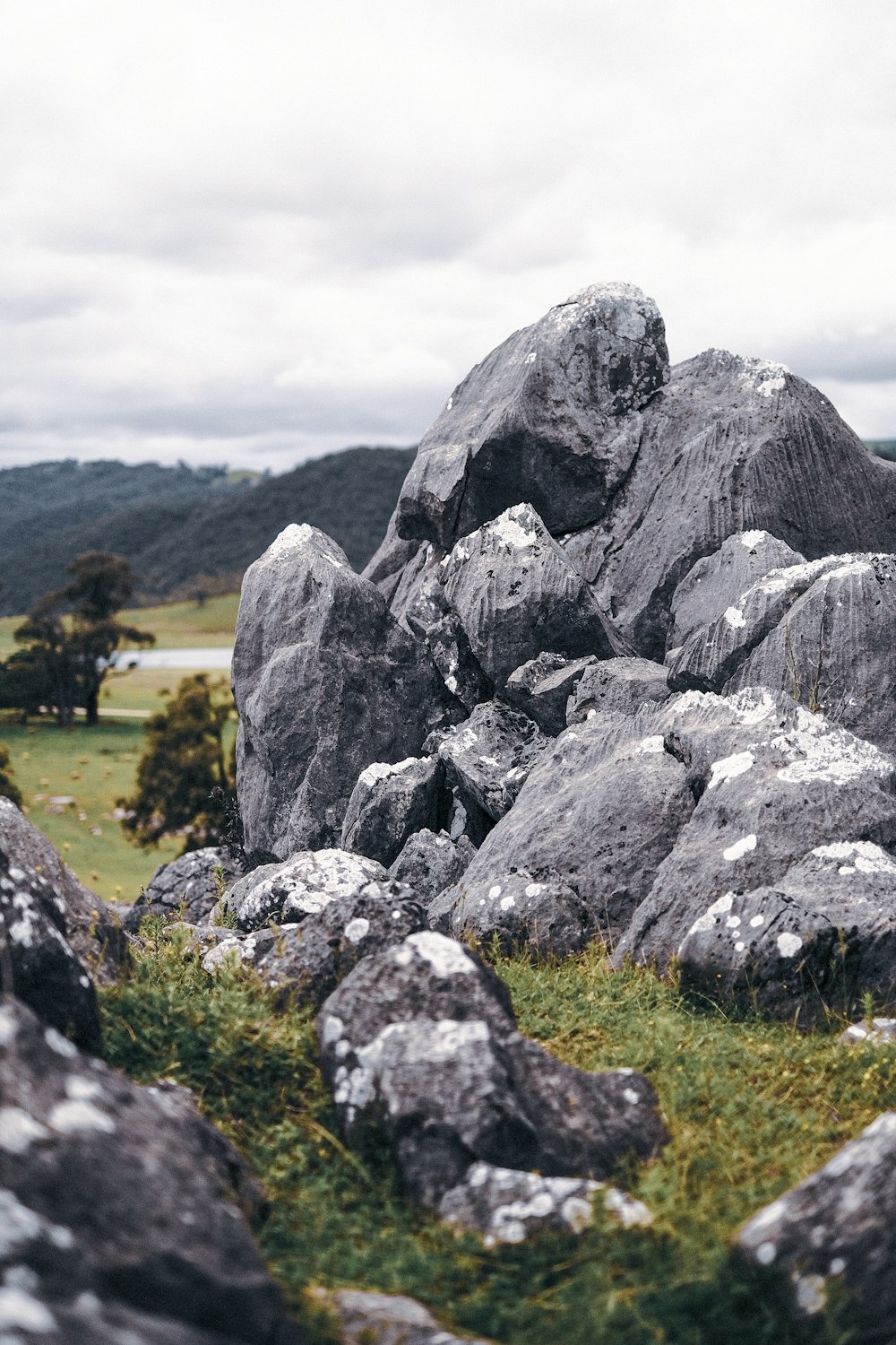 昼間の緑の芝生の上の灰色の岩層
