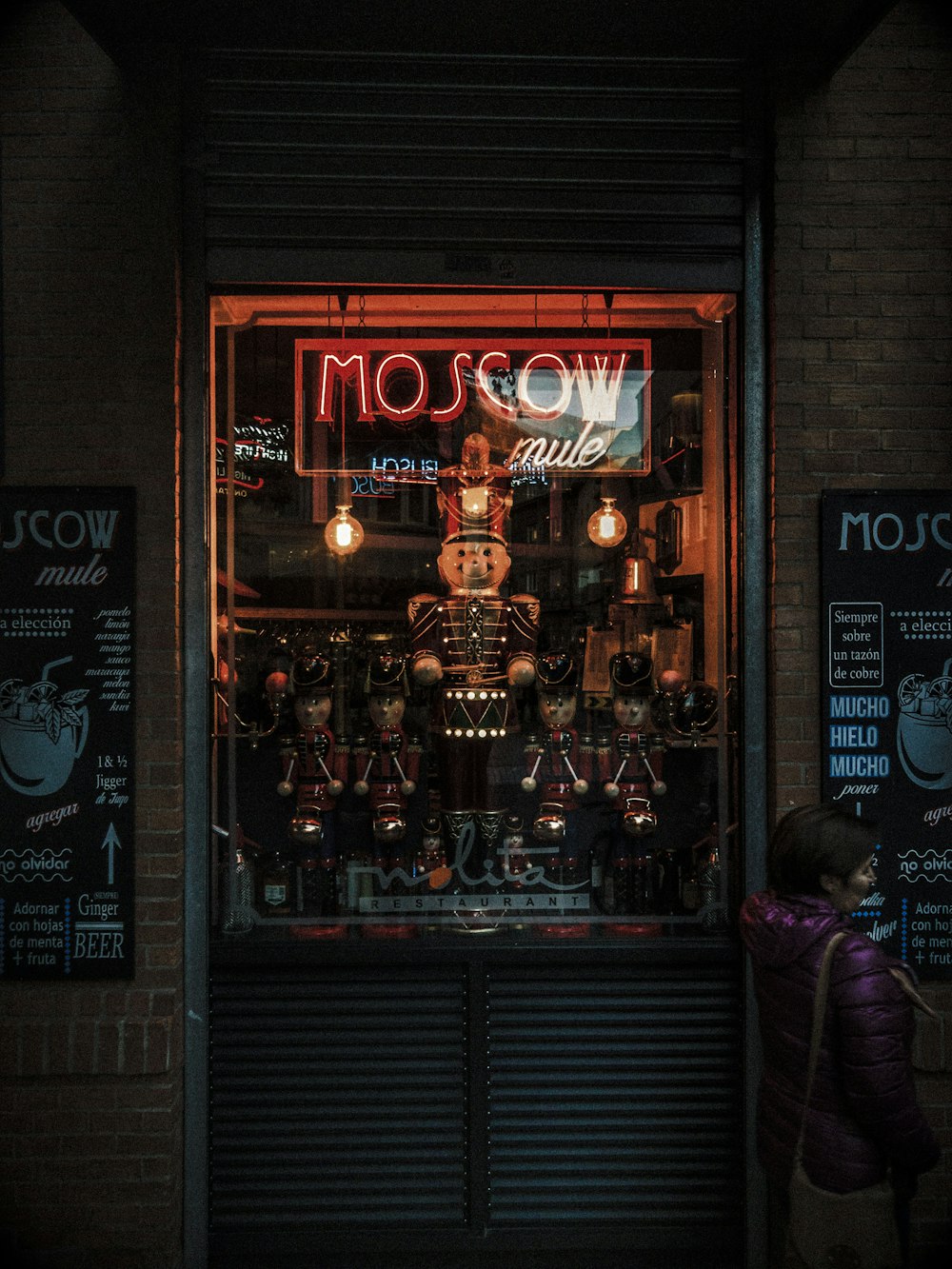 woman in purple jacket standing in front of brown wooden store