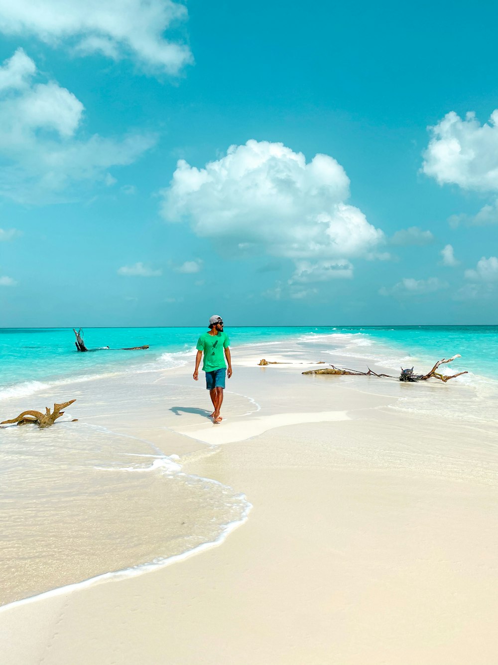 청록색 드레스를 입은 여자가 낮 동안 해변을 걷고 있다