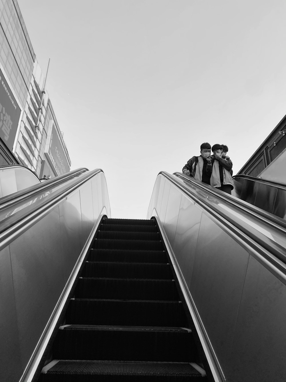 grayscale photo of 2 women on escalator