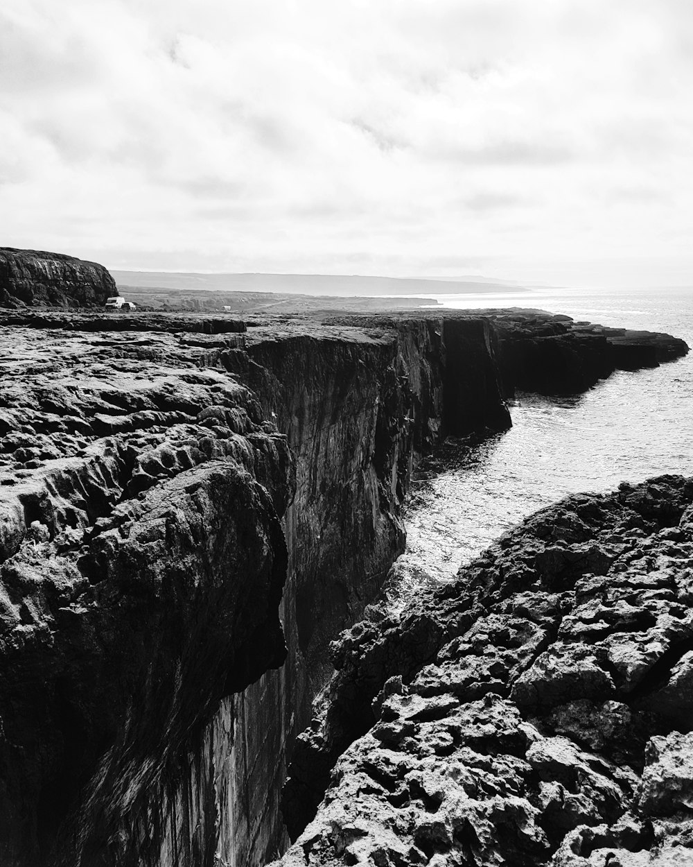 grayscale photo of rocky mountain beside sea