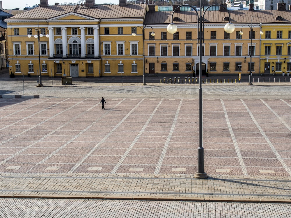 people walking on sidewalk near yellow concrete building during daytime