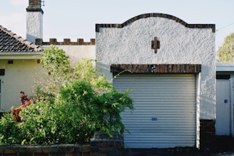green plants beside white concrete building during daytime
