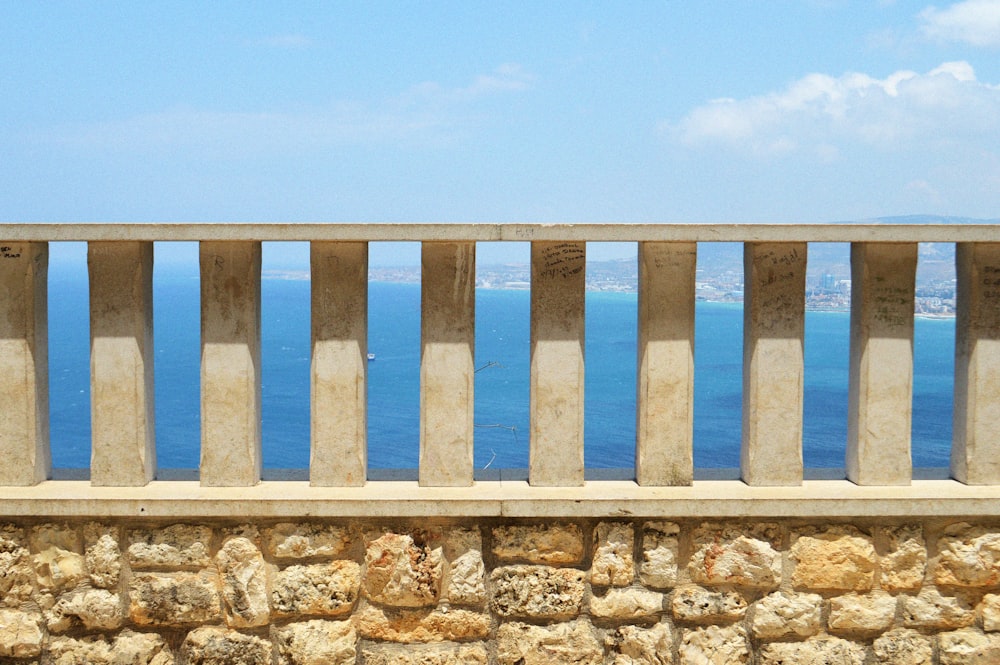 white wooden fence on rocky shore during daytime