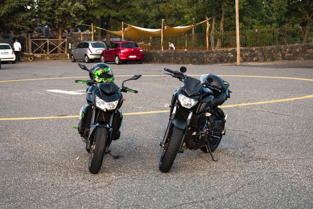 black and green motorcycle parked on gray asphalt road during daytime