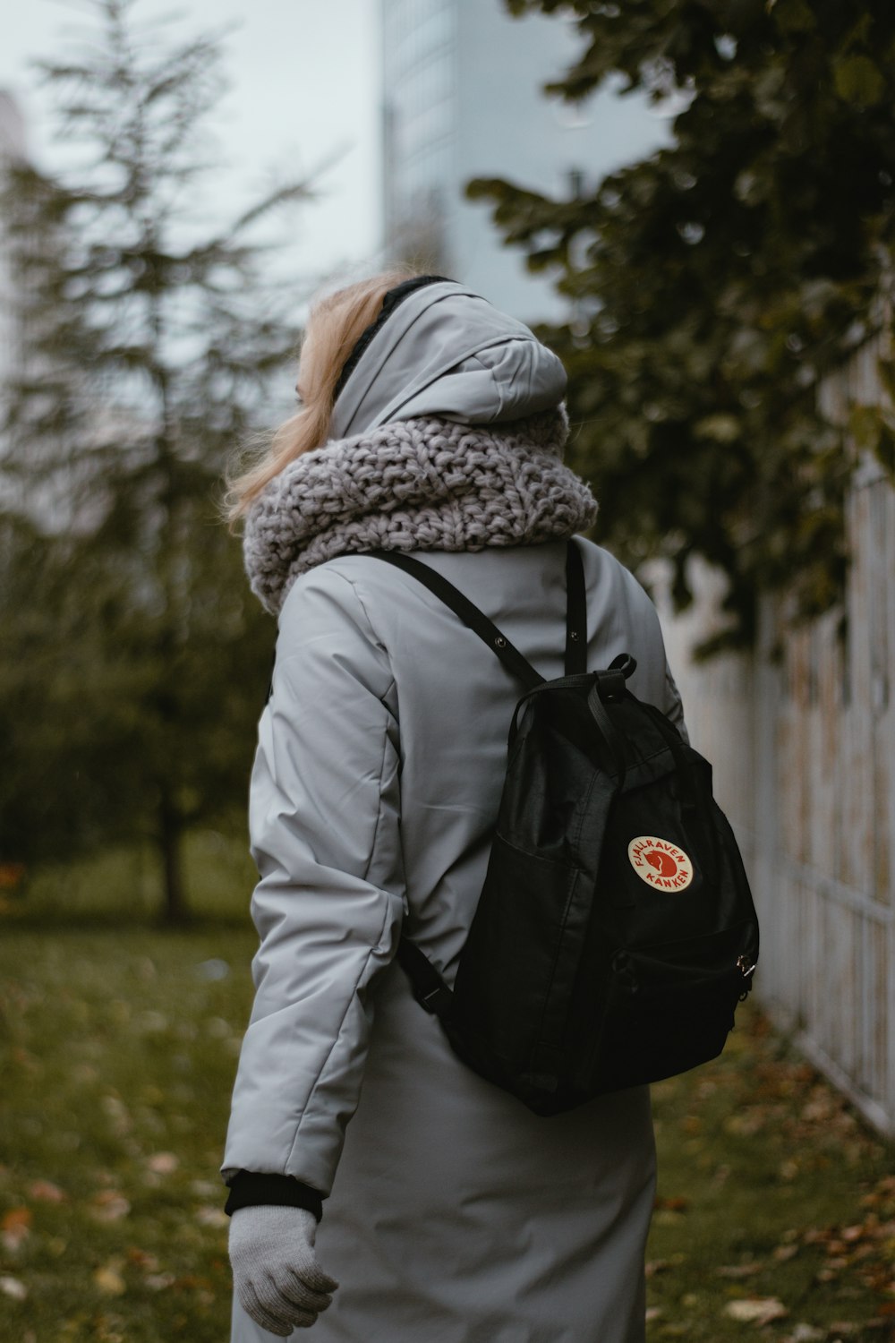 woman in gray jacket and black backpack standing on green grass field during daytime