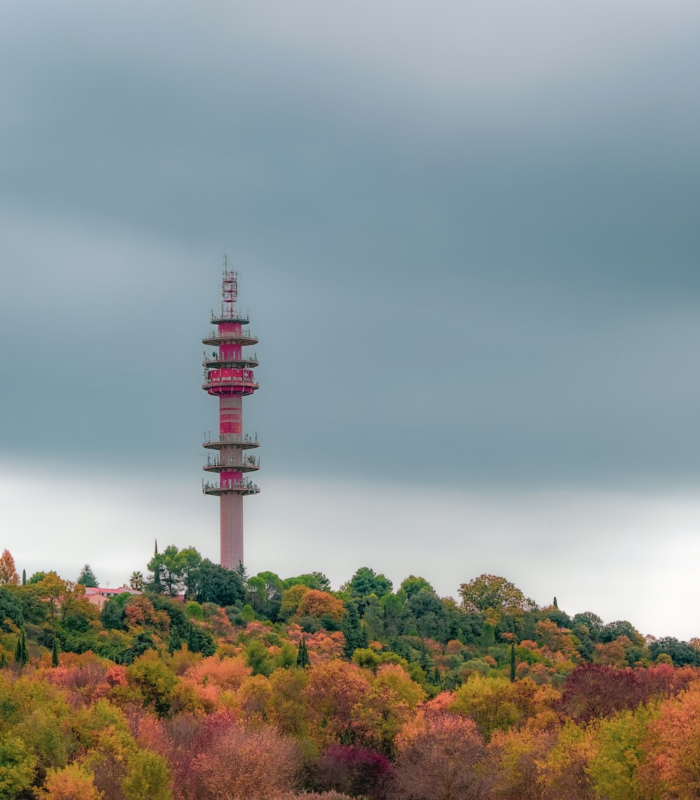 torre vermelha e branca cercada por árvores verdes sob o céu cinzento