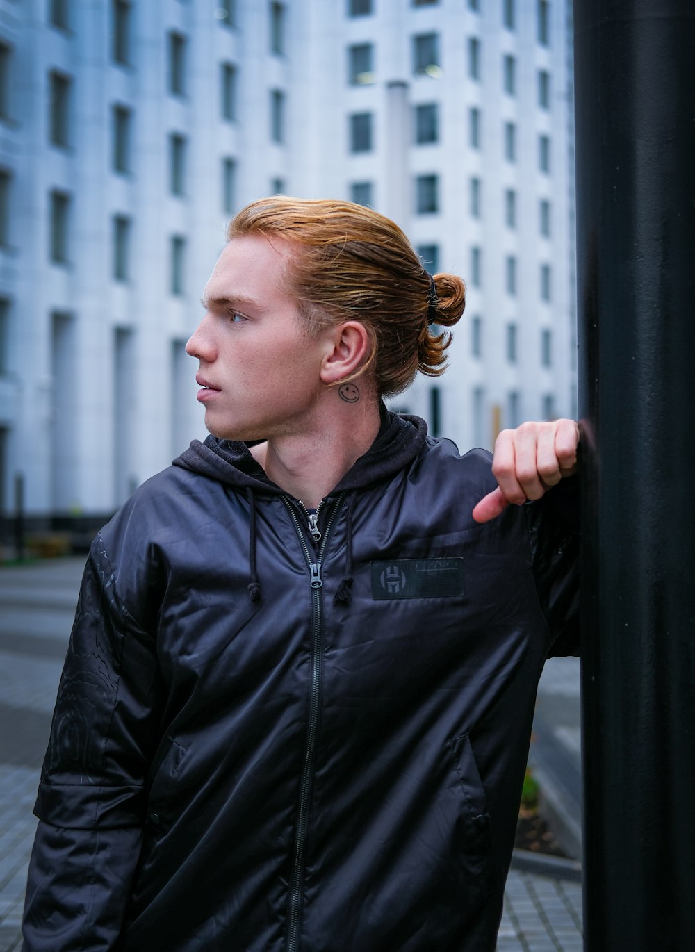 man in black leather jacket standing beside black metal fence during daytime