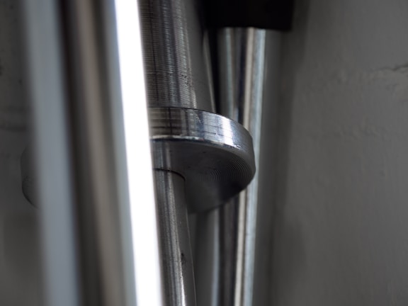 Close-up of shiny steel rods stacked neatly in a warehouse with orange lighting.
