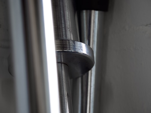 Close-up of shiny steel rods neatly stacked, reflecting light in a large warehouse.