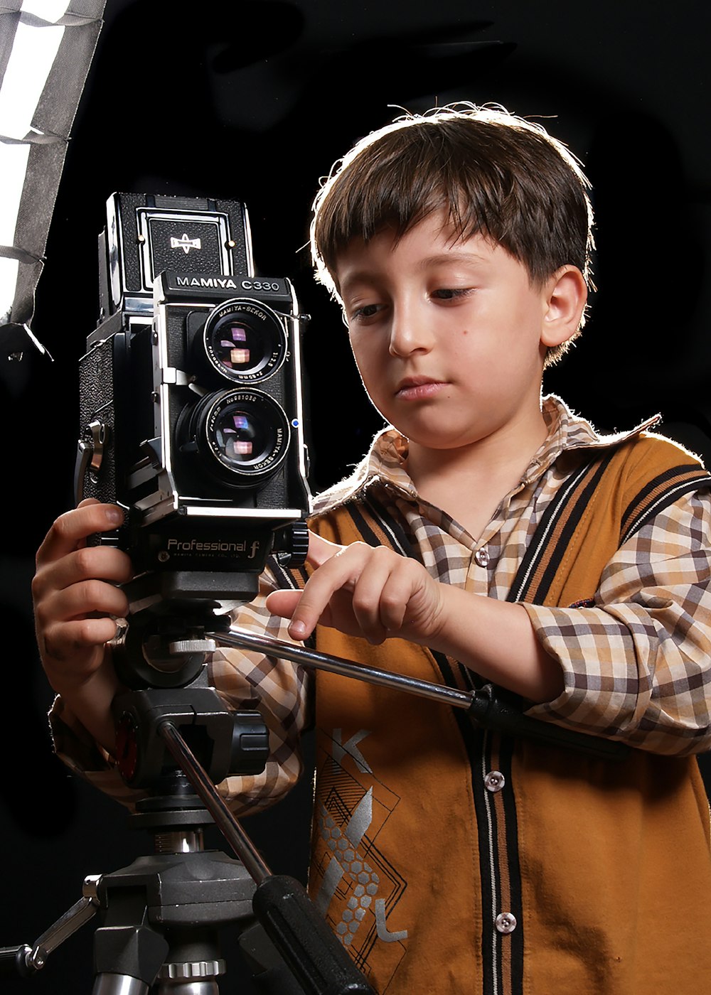 boy in brown and white plaid button up shirt holding black camera