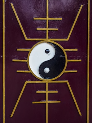 A yin-yang symbol is centered on a purple panel with a golden geometric design that radiates outward, creating a symmetrical and balanced aesthetic.