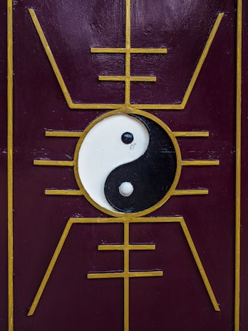 A yin-yang symbol is centered on a purple panel with a golden geometric design that radiates outward, creating a symmetrical and balanced aesthetic.