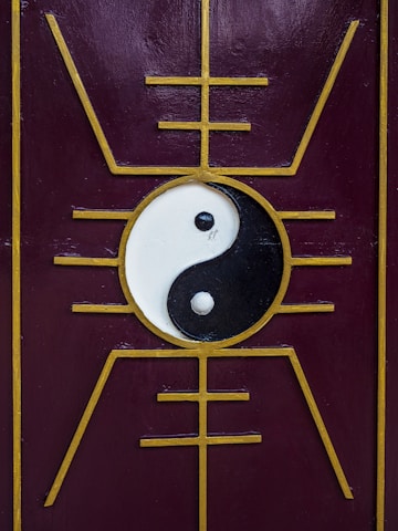 A yin-yang symbol is centered on a purple panel with a golden geometric design that radiates outward, creating a symmetrical and balanced aesthetic.