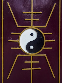 A yin-yang symbol is centered on a purple panel with a golden geometric design that radiates outward, creating a symmetrical and balanced aesthetic.