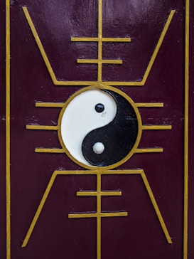 A yin-yang symbol is centered on a purple panel with a golden geometric design that radiates outward, creating a symmetrical and balanced aesthetic.