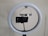 A circular LED ring light is mounted on a stand, with a smartphone attached in the center of the ring using a holder. The setup appears to be prepared for recording or streaming purposes.