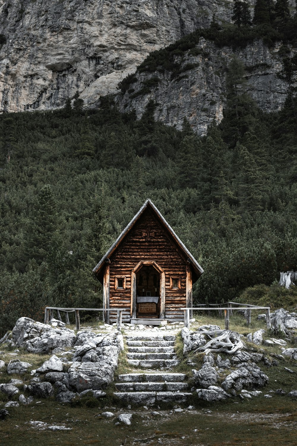 brown wooden house near green trees and mountain during daytime