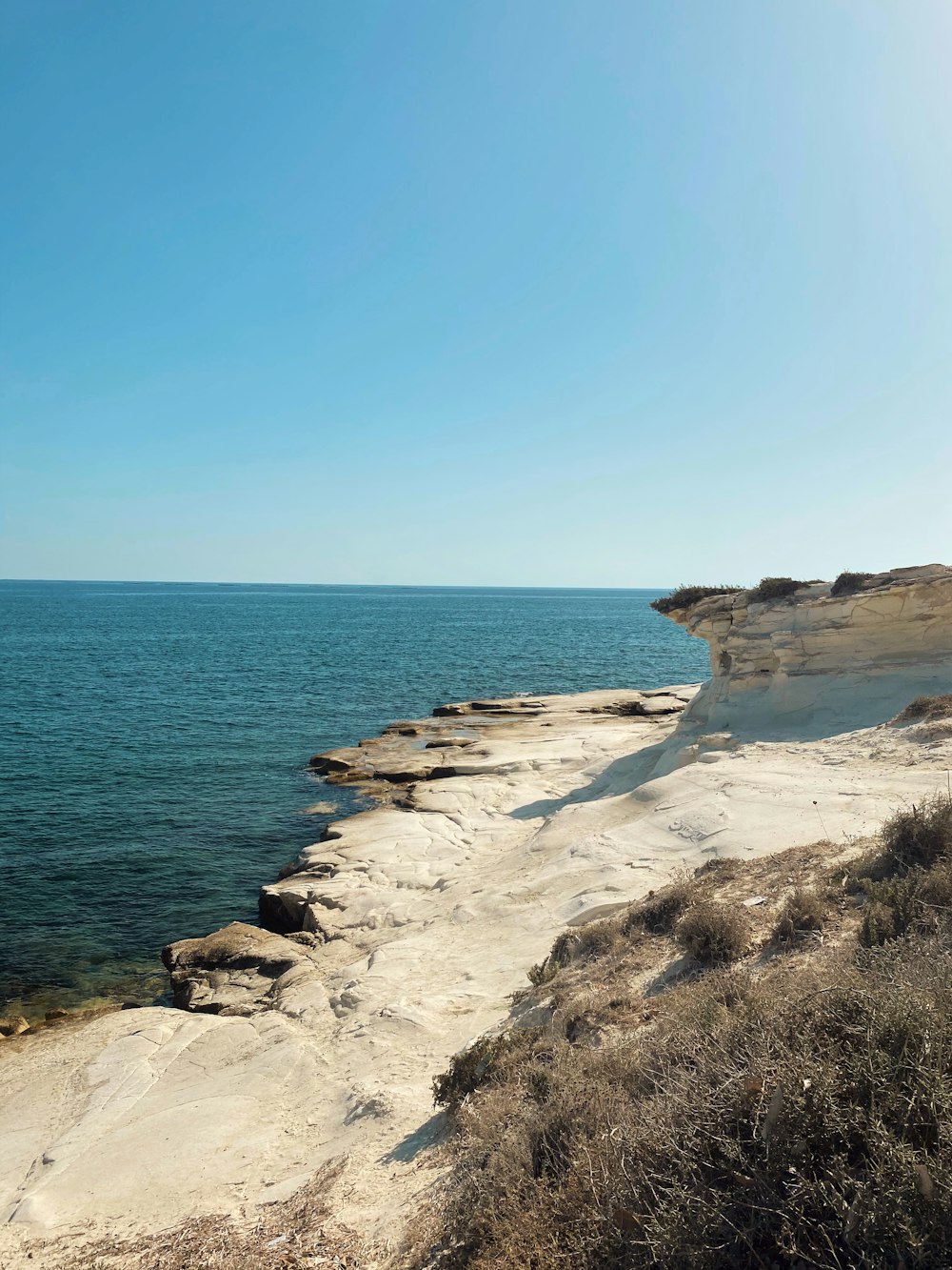 brown rocky shore near blue sea under blue sky during daytime