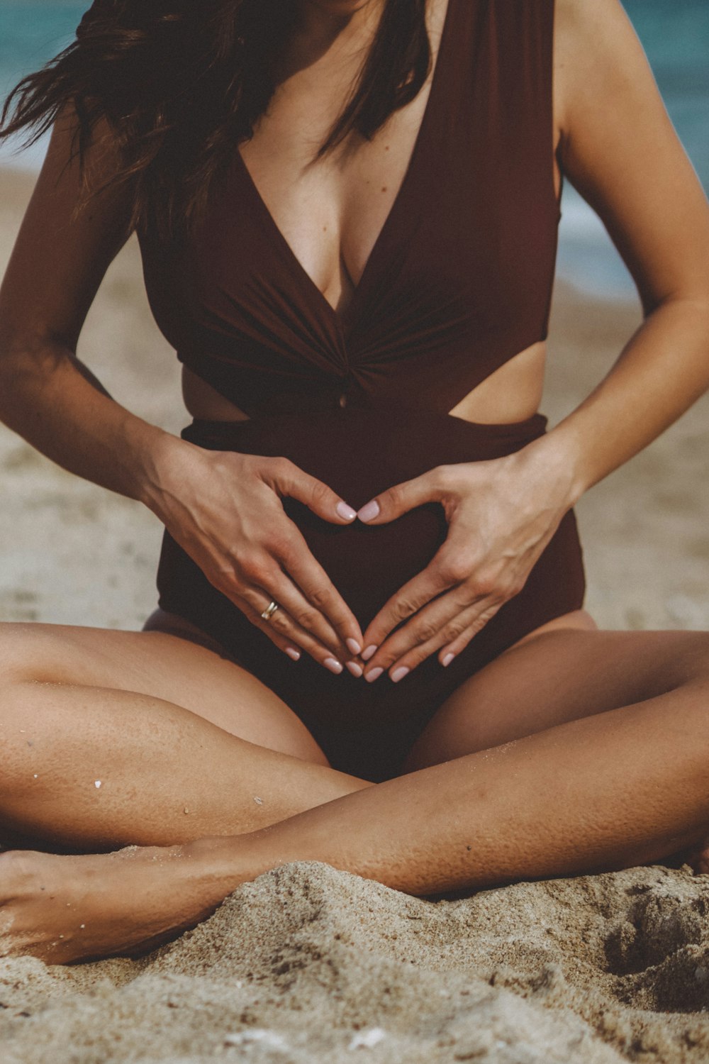 woman in black one piece swimsuit sitting on sand during daytime