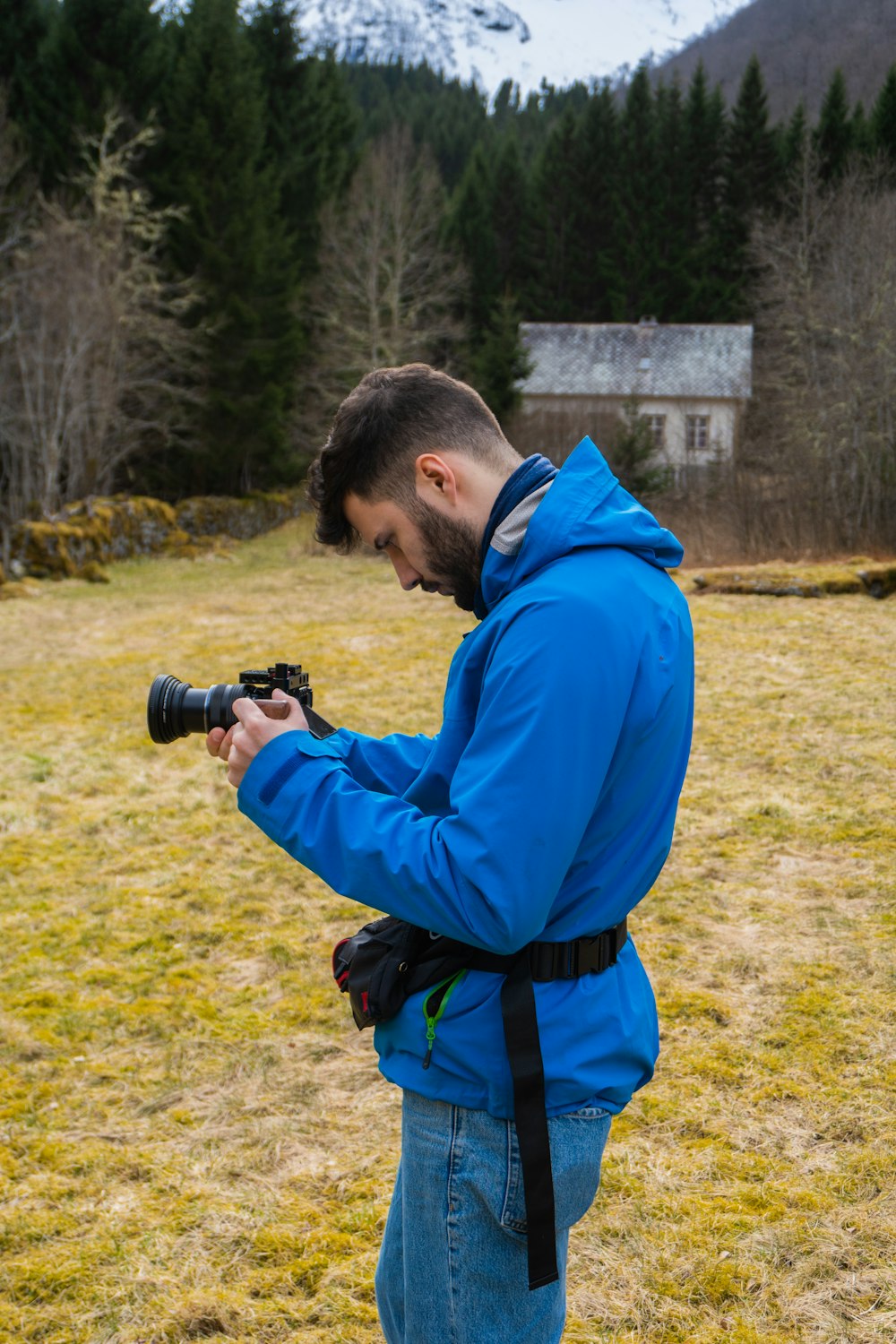 man in blue jacket holding black dslr camera