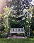 A rustic wooden garden bench surrounded by blooming flowers and climbing vines.
