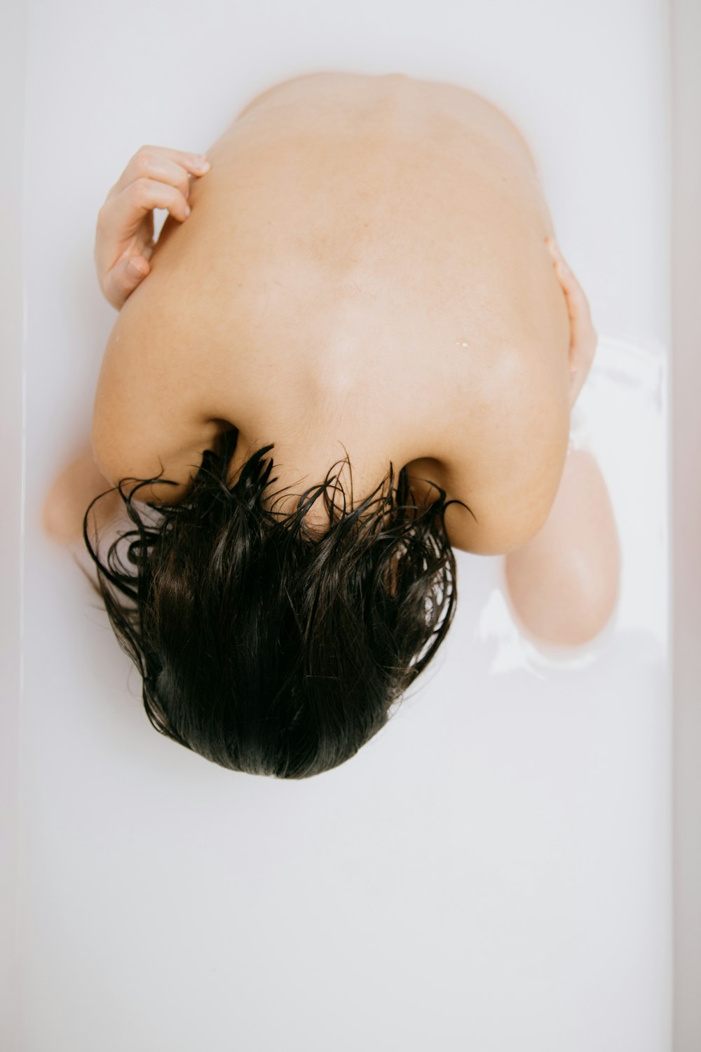 womans head on white bathtub