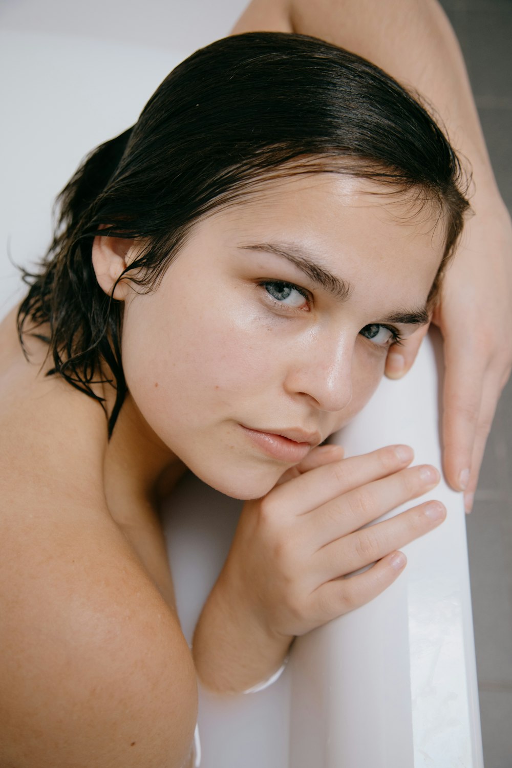 topless woman with left hand on her cheek