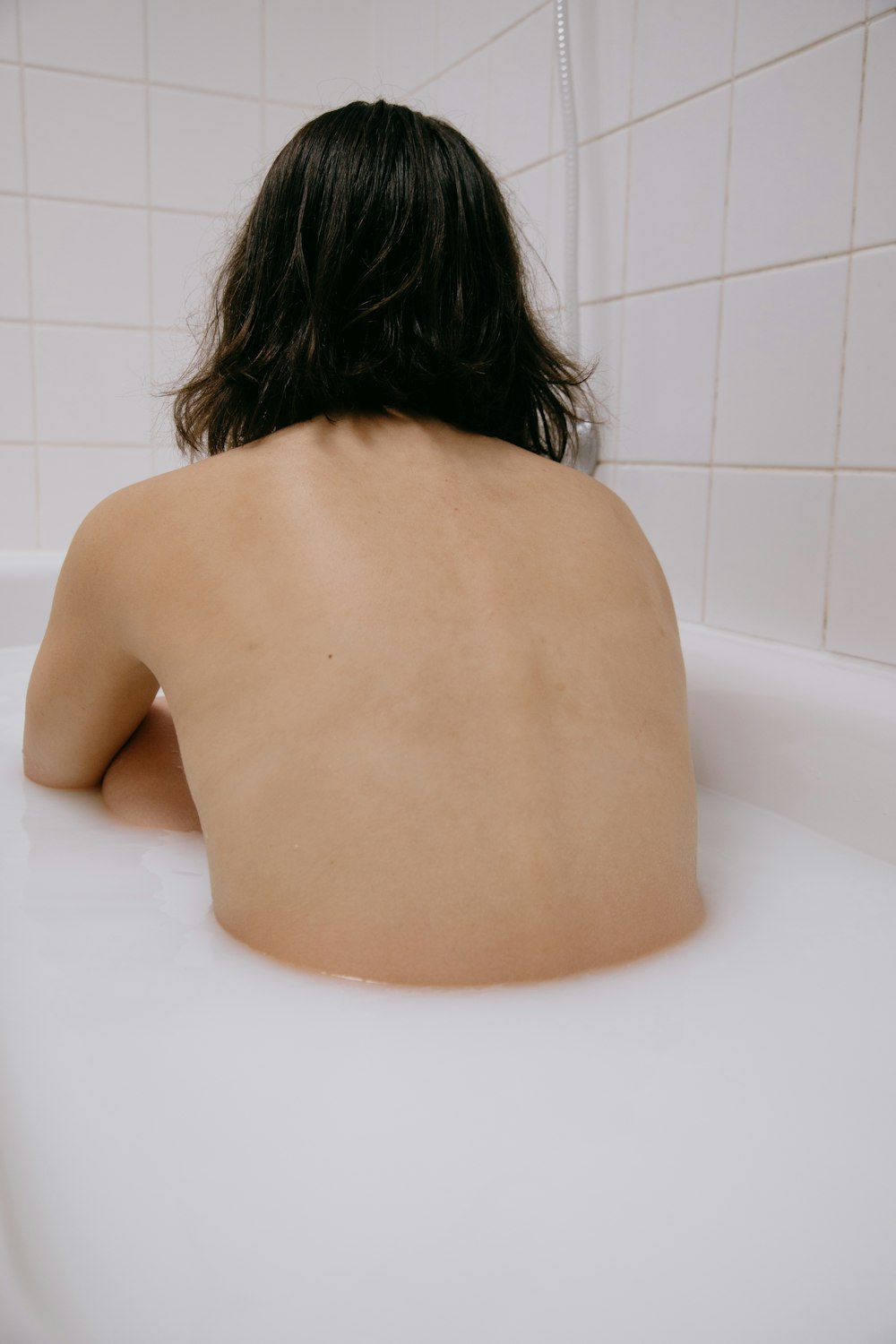 白い浴槽の上の裸の女性