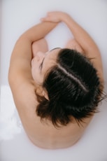 woman lying on white bathtub
