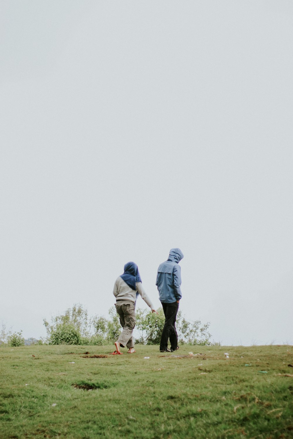 man in blue jacket and black pants walking on green grass field during daytime