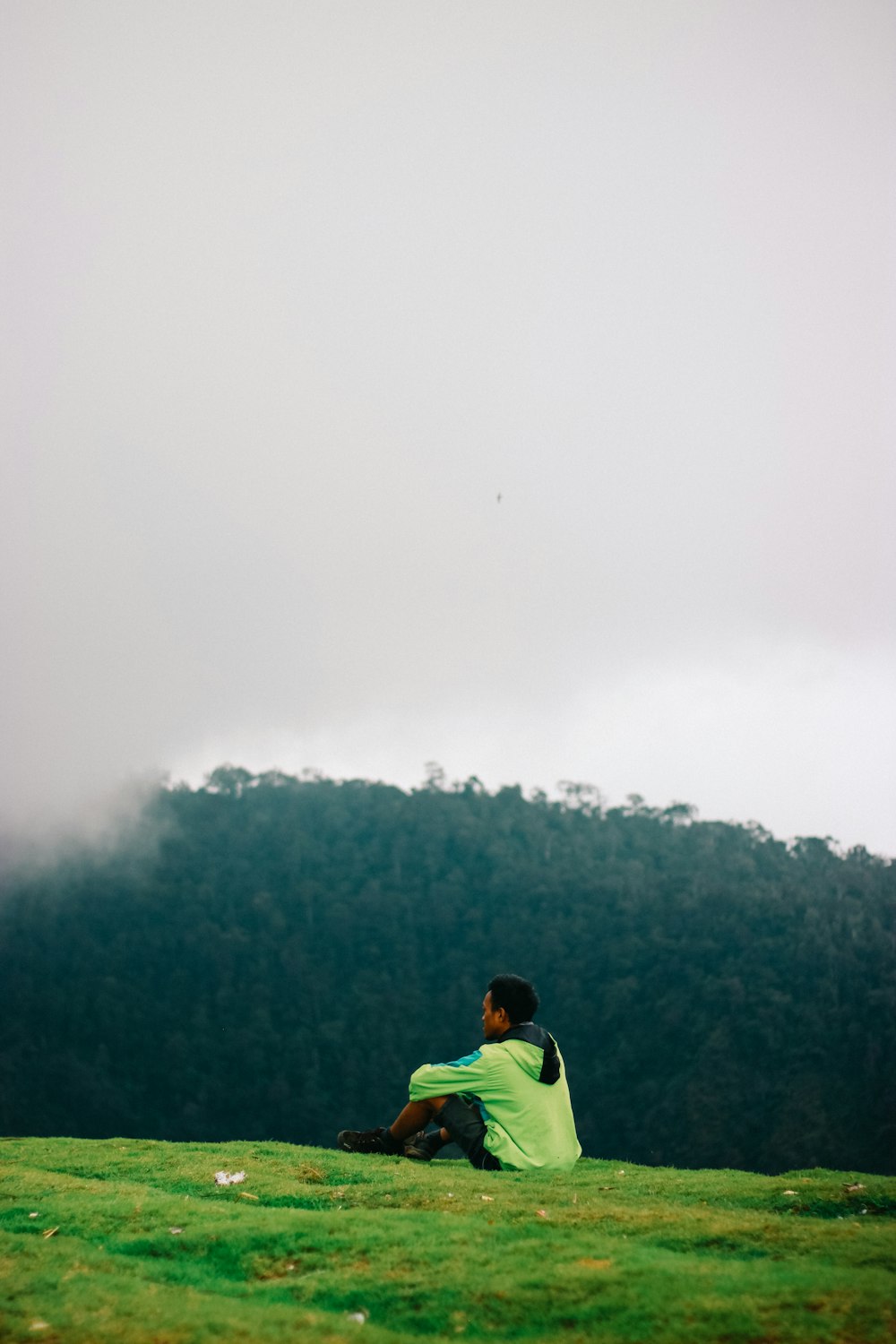 man in green shirt standing on green grass field during foggy weather