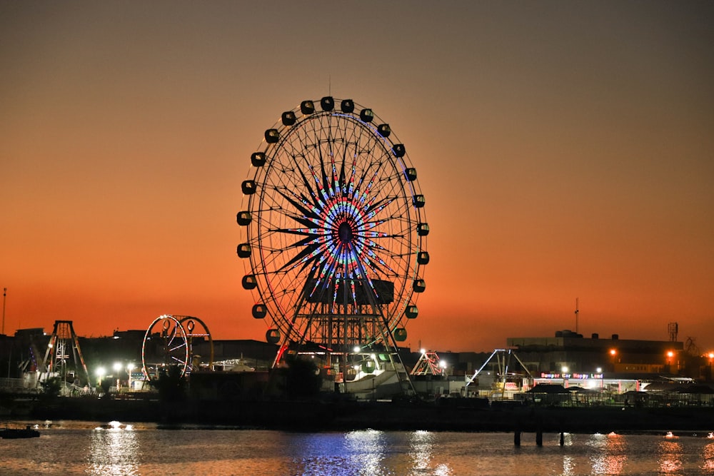 ferris wheel near body of water during sunset