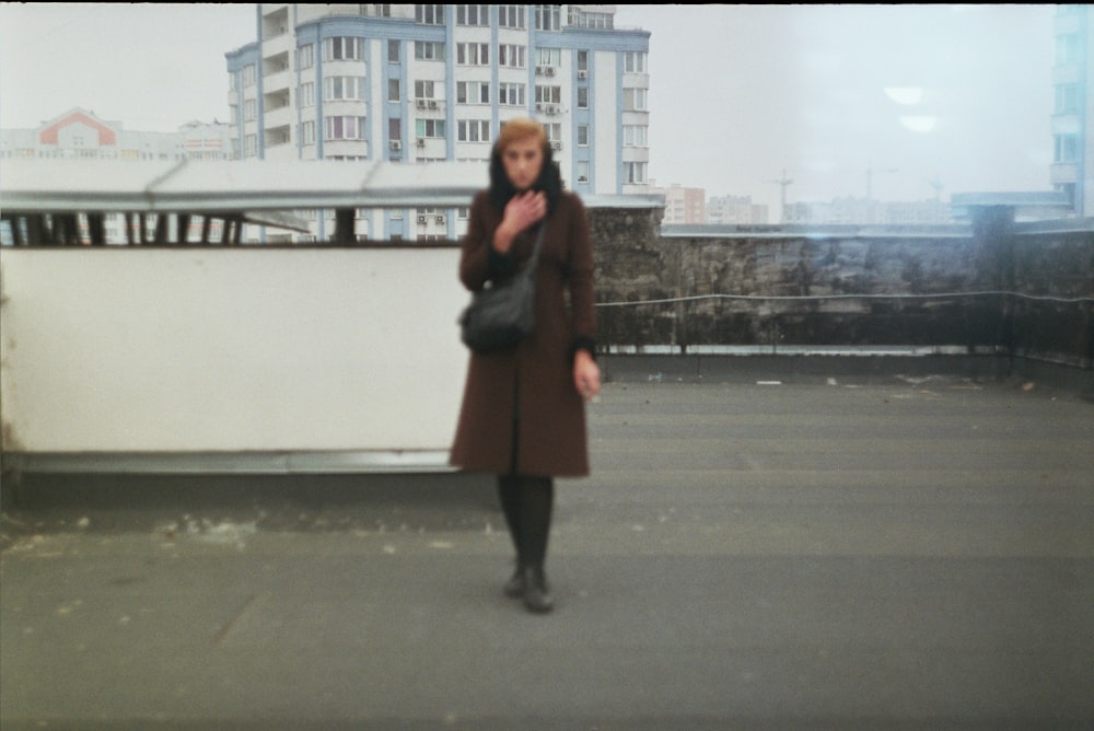 woman in black coat standing on gray concrete road