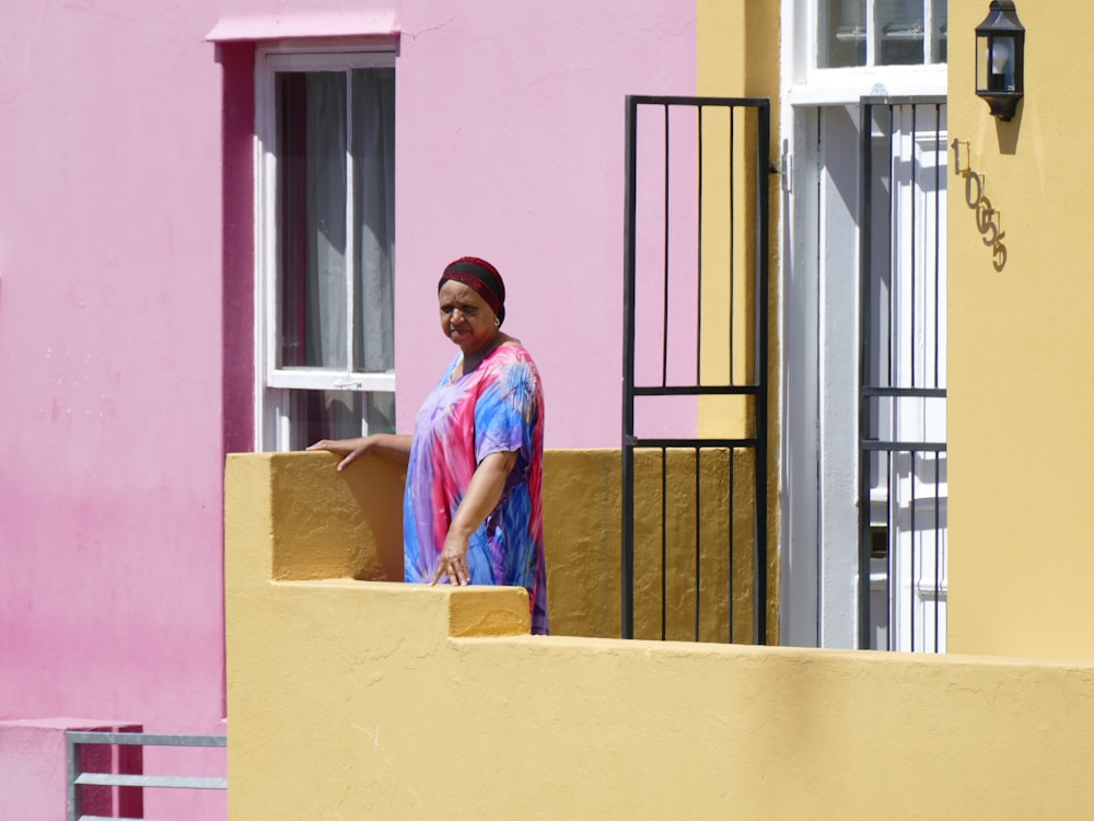 man in blue button up shirt standing beside pink concrete wall during daytime