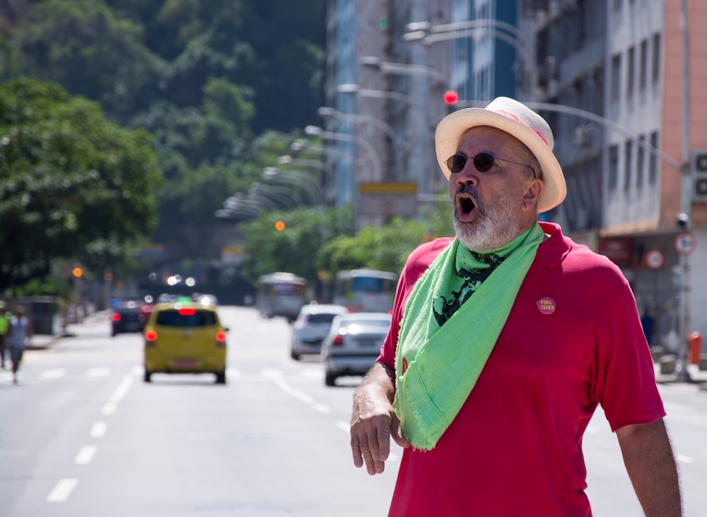 man in red polo shirt and green vest standing on road during daytime