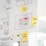 A whiteboard or wall is filled with paper sheets and sticky notes containing diagrams, sketches, and notes. Prominent features include hand-drawn flowcharts with symbols and arrows, as well as several colored sticky notes with handwritten words like 'Feedback' and 'Infos + Features'. The central sheet displays a layout with text and colored dots, possibly representing an interface design or process.