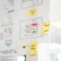 A whiteboard or wall is filled with paper sheets and sticky notes containing diagrams, sketches, and notes. Prominent features include hand-drawn flowcharts with symbols and arrows, as well as several colored sticky notes with handwritten words like 'Feedback' and 'Infos + Features'. The central sheet displays a layout with text and colored dots, possibly representing an interface design or process.
