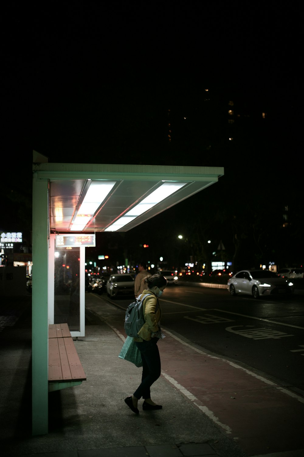 man in green jacket walking on sidewalk during night time