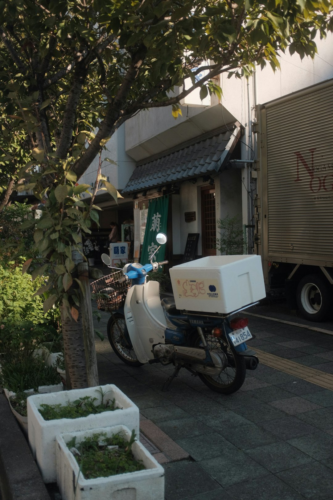 white and black motorcycle parked beside green tree during daytime