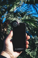 Hand holding a phone with a custom floral design case against a sunny background.
