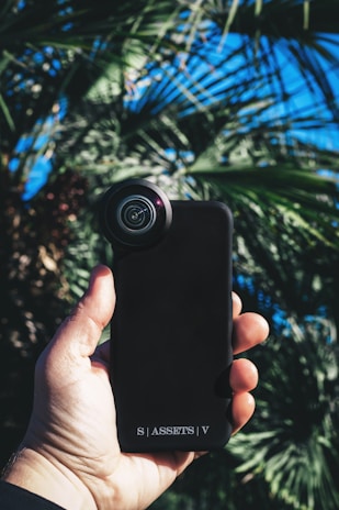 Happy customer holding their phone with an Elite Phone accessory in a sunny outdoor setting.