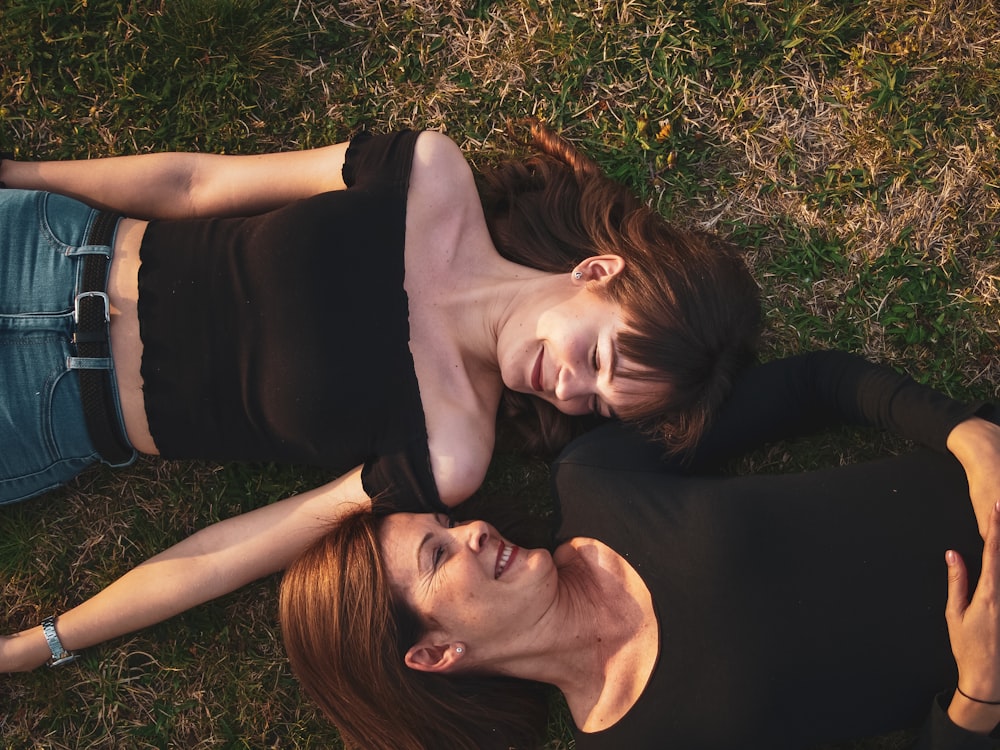 woman in black sleeveless dress lying on green grass field