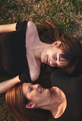 woman in black sleeveless dress lying on green grass field